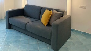 Ein modernes Wohnzimmer mit einem grauen Sofa, einem gelben Kissen und einem weißen Kleiderschrank.