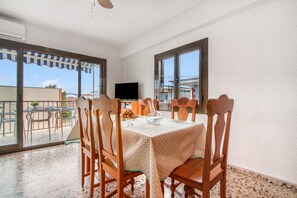 Un comedor con una mesa dispuesta para seis personas, un televisor y vistas al exterior.