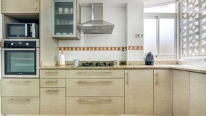 A kitchen with built-in appliances, a window with a view, and a decorative backsplash.