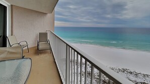 Ein Balkon mit Blick auf den Ozean, ein Stuhl und ein Glastisch.