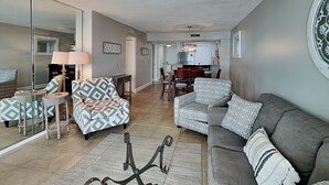 Ein Wohnzimmer mit einer Couch, Sesseln und einem Essbereich mit Stühlen und Tisch.