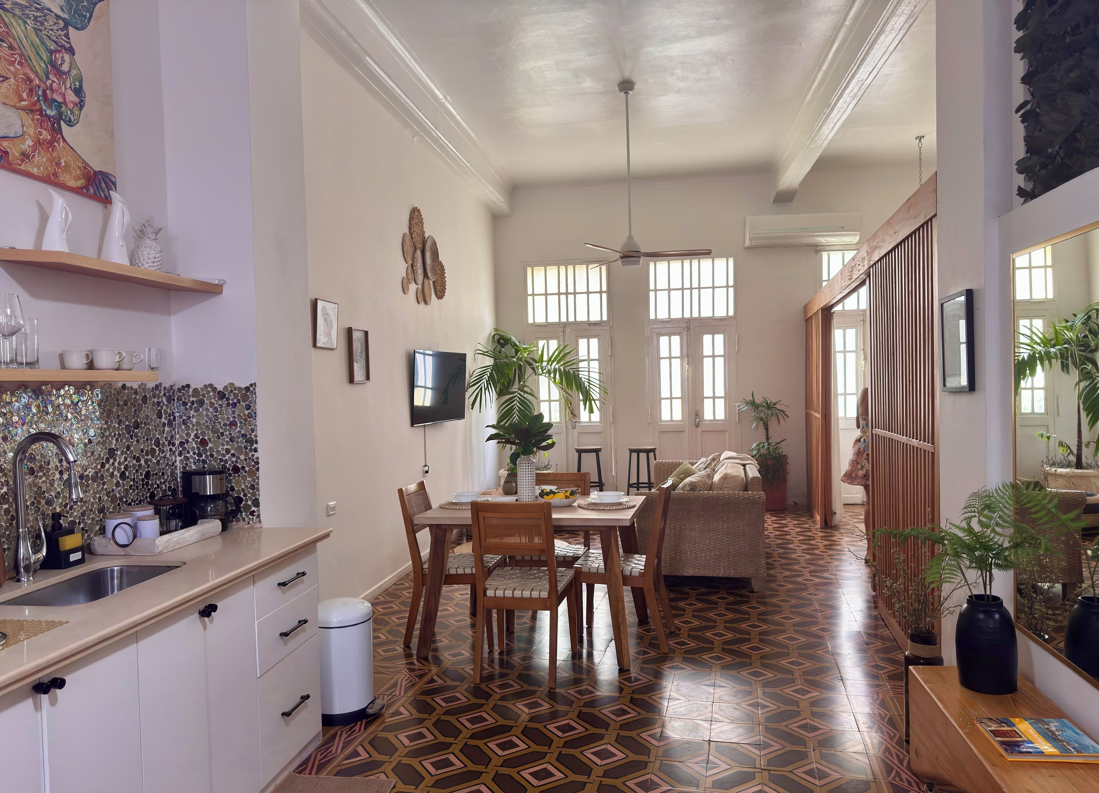 Una cocina amplia con suelo de baldosas, un comedor con mesa y sillas, y una sala de estar con sofá.