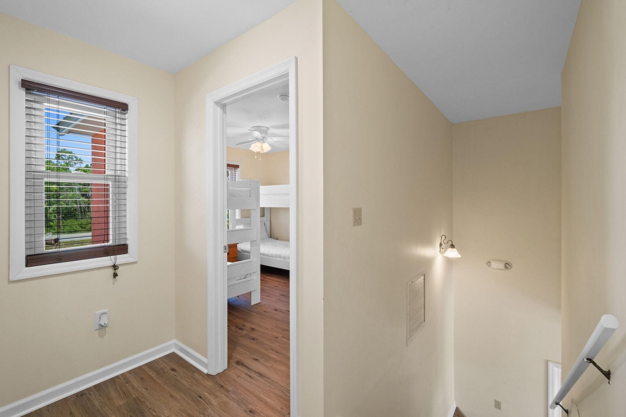 Une chambre à coucher avec un lit, un ventilateur de plafond et une fenêtre avec des stores.