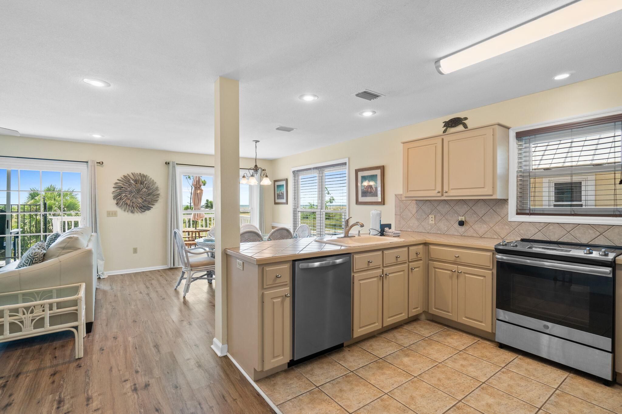 A modern kitchen with beige cabinets, a stainless steel dishwasher, and a built-in oven.