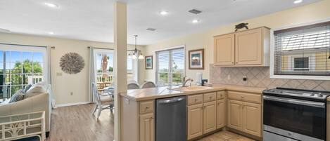 A modern kitchen with beige cabinets, a stainless steel dishwasher, and a built-in oven.