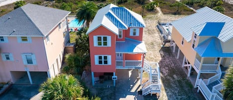 A coastal property with a two-story house featuring a blue roof, a pink house, and a beige house with a blue roof.