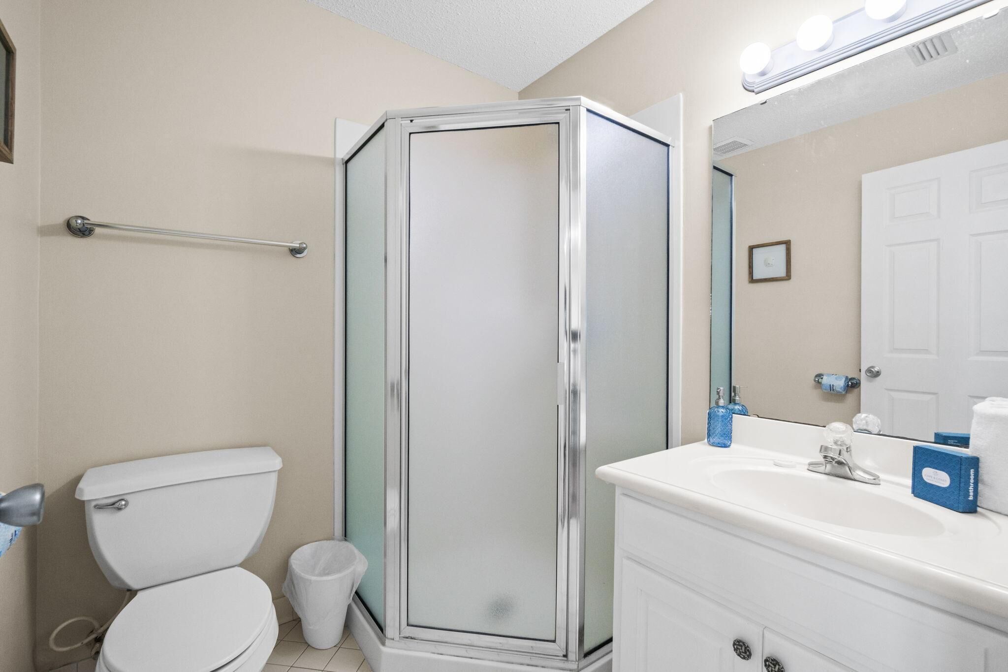 A bathroom with a toilet, a glass-enclosed shower, a sink, and a mirror.
