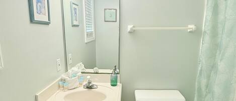 A bathroom with a vanity, sink, mirror, and toilet.