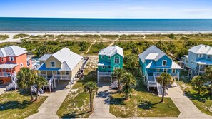 A beachfront property with colorful houses, a sandy beach, and a clear view of the ocean. - All Decked Out (Port St. Joe)