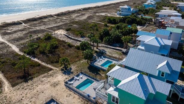 A coastal property with a swimming pool, beachfront view, and multiple houses with blue roofs.