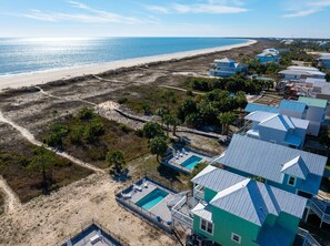Una propiedad costera con piscina, vista a la playa y varias casas con techos azules.