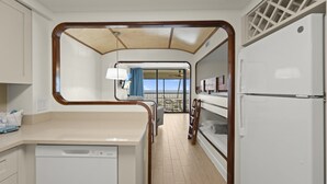A compact kitchen with a dishwasher, a refrigerator, and a dining area with a view of the sea. - Mariners Boathouse by Coolvacay (Fort Myers Beach)