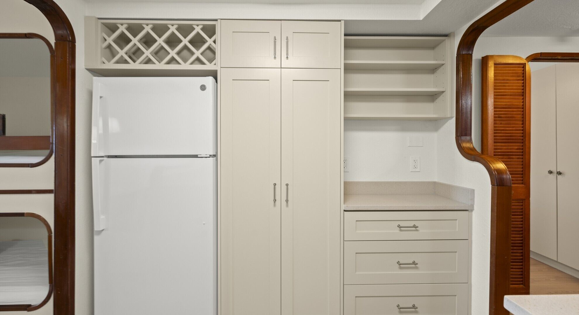 A walk-in closet with a white refrigerator, a set of drawers, and a shelving unit.