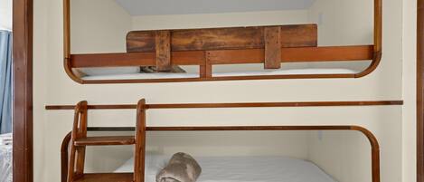 A bunk bed with a wooden ladder and a rolled-up blanket on the lower bunk.