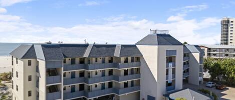 Un hotel de varios pisos con techo plano y balcones, cerca de la playa.
