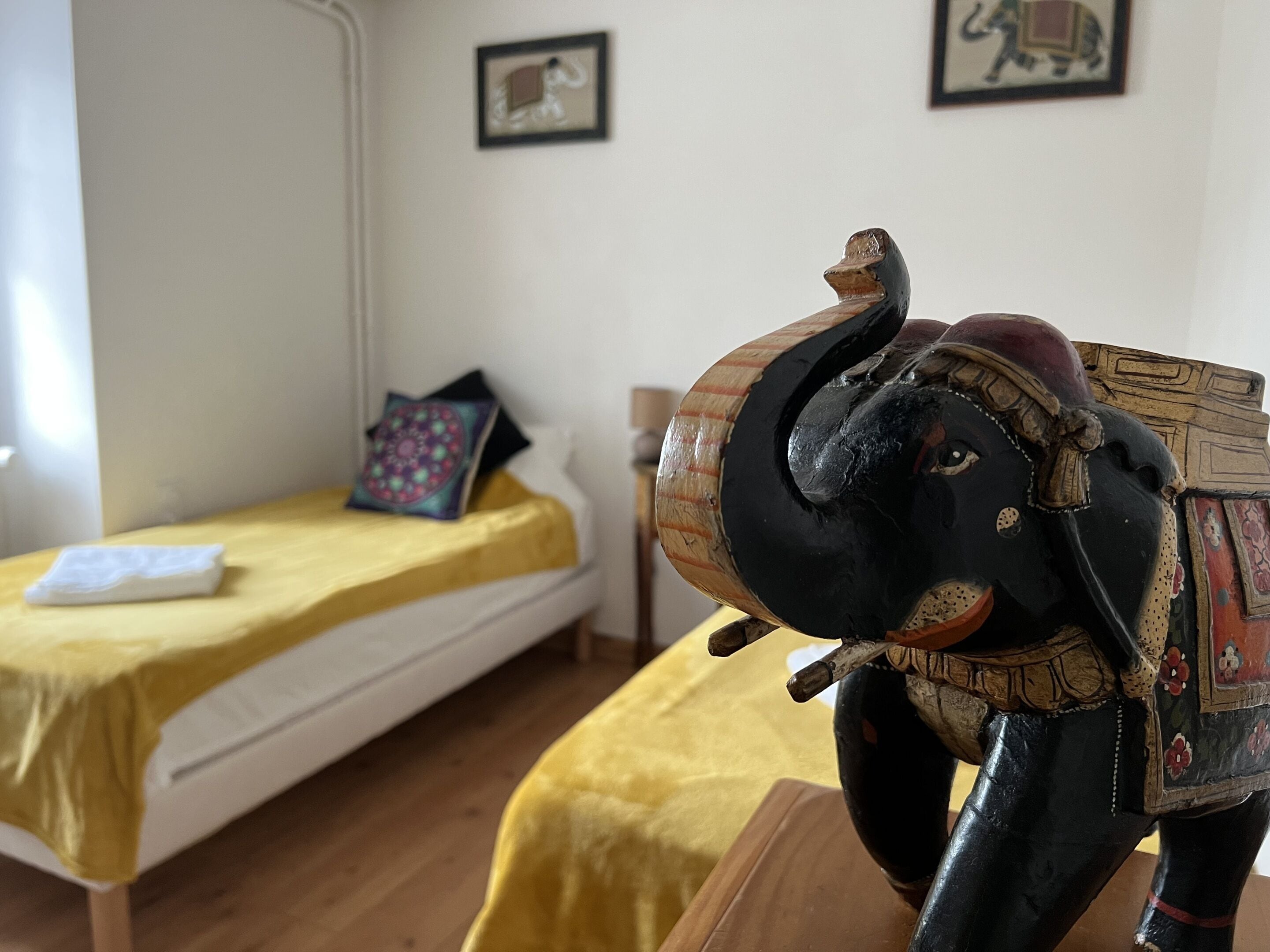 A room with a bed, a small table, and a decorative elephant sculpture.