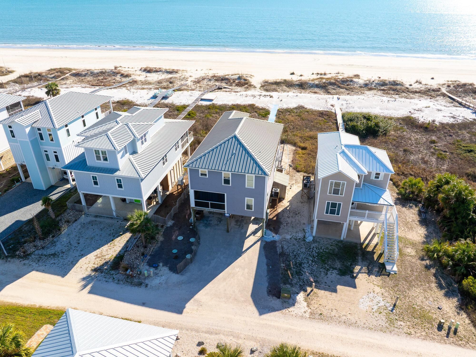A beachfront property with multiple houses, a sandy beach, and a clear view of the ocean.