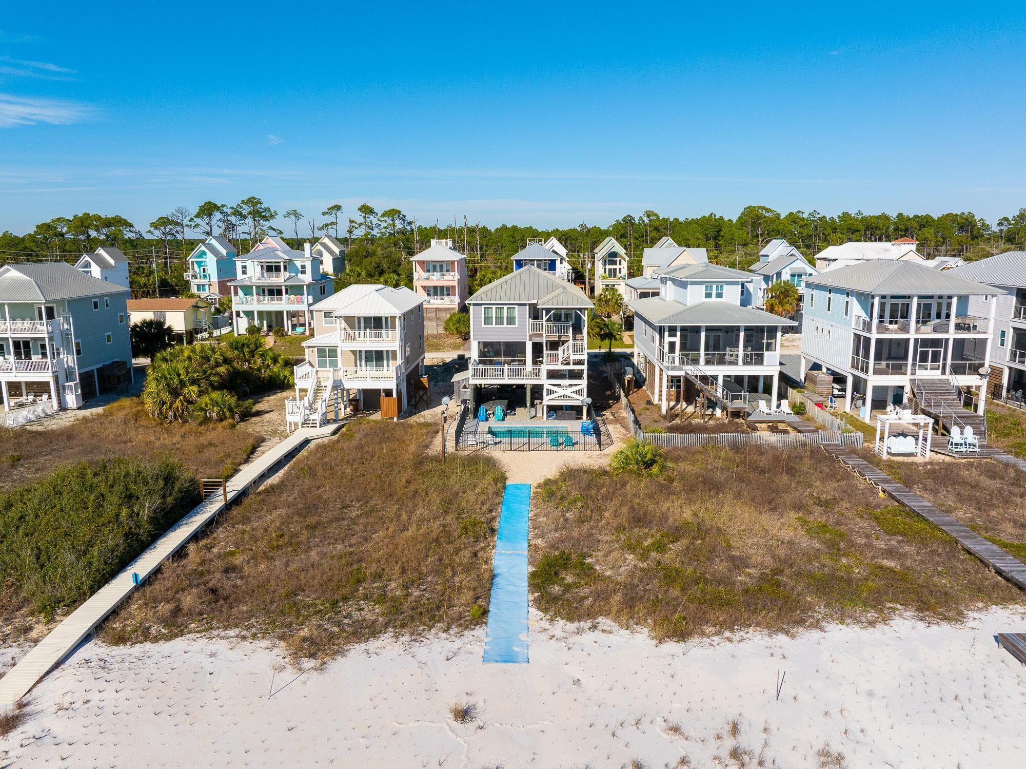 A coastal residential area with beachfront properties featuring balconies, a swimming pool, and a boardwalk.