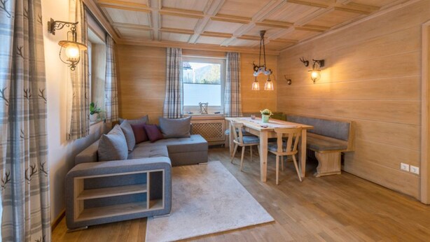 Een gezellige woonkamer met een hoekbank, een eettafel en een bankje.