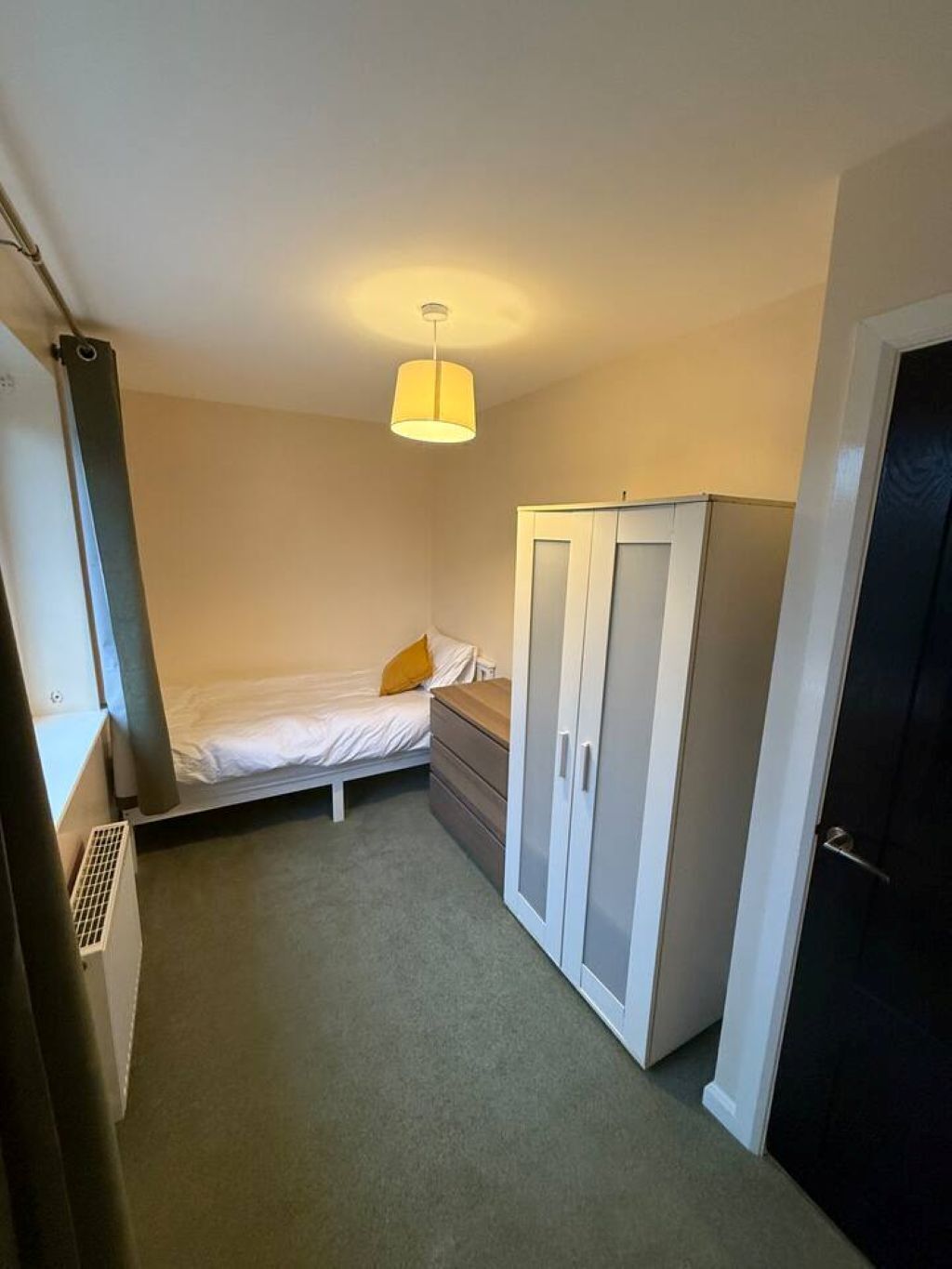 A small, narrow room with a single bed, a wardrobe, and a radiator.