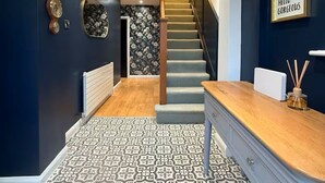 Un interior moderno con una escalera que lleva a un segundo piso, un suelo estampado y un letrero con la frase 'Hello Gorgeous' en la pared.