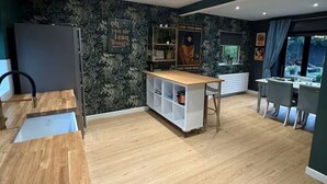 Una cocina moderna con encimera de madera, un armario empotrado blanco y un comedor con mesa y sillas.