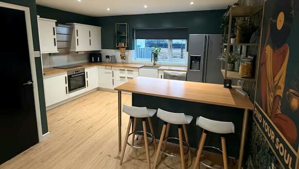 Una cocina moderna con una isla central, taburetes de bar y vistas al exterior.