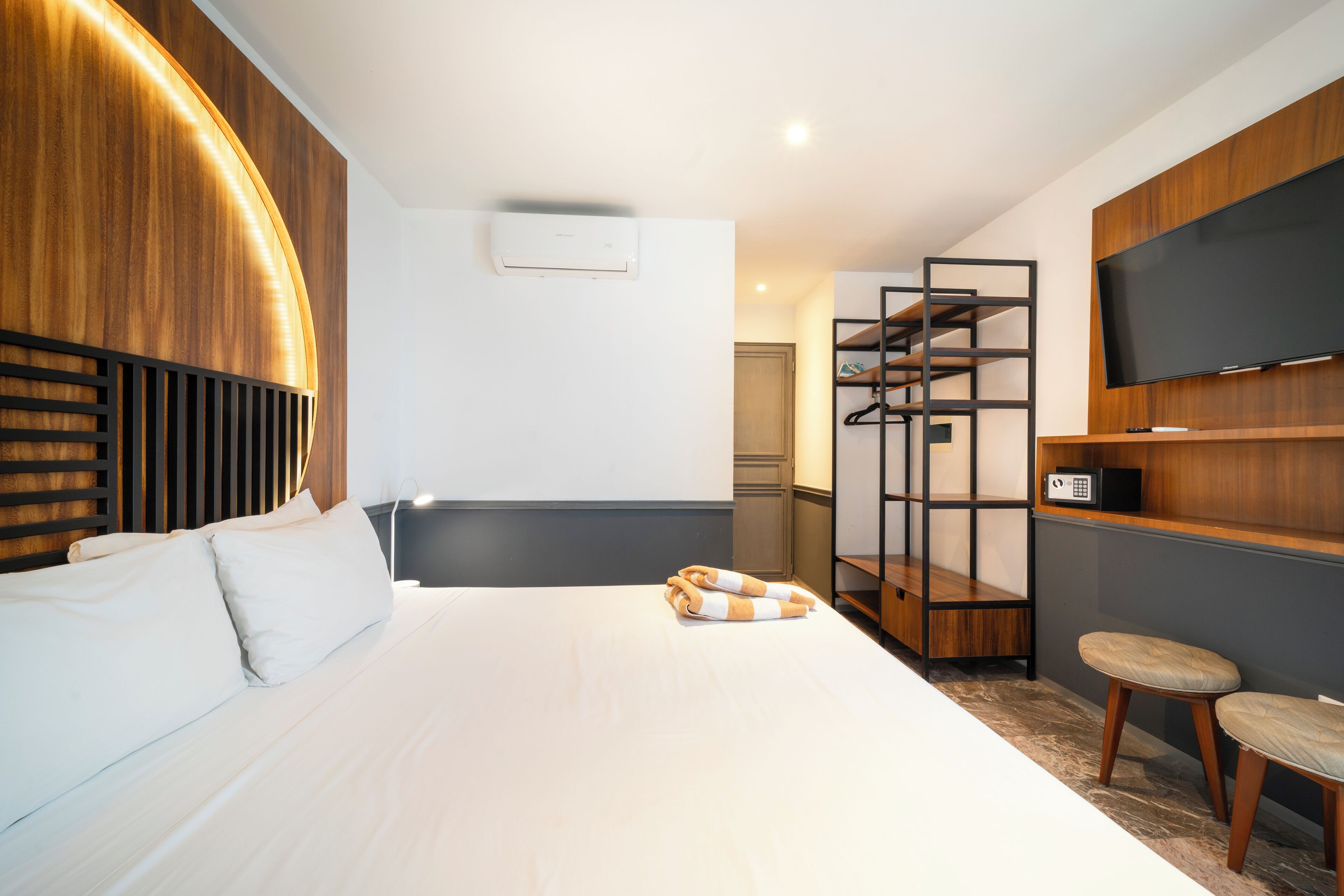 Quarto de hotel moderno com uma cama grande, televisão, guarda-roupa e zona de estar.