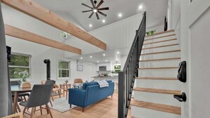 A spacious living area with a blue sofa, wooden flooring, and a staircase with wooden steps.