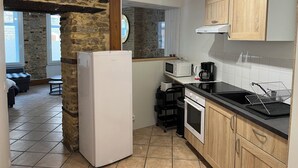 A compact kitchen with a stone wall, a refrigerator, a microwave, a coffee maker, and wooden cabinets.