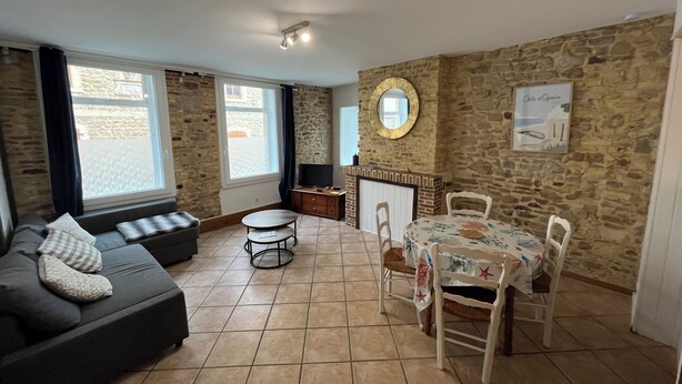 A living room with a stone wall, a sofa, a dining table with chairs, and a television.
