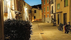 A narrow street with buildings on either side, a paved walkway, and bicycles parked near the buildings. - Between sea and mountains, pets welcome, hiking, walks from the house (Revest-les-Roches)