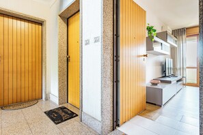 A modern hotel lobby with wooden doors, a granite floor, a reception desk, and a plant on a shelf. - Elegant panoramic openspace a few steps from the sea (Quartu Sant'Elena)