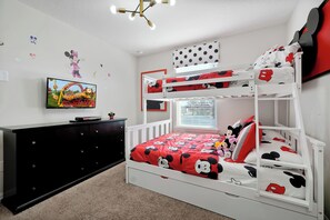 A bunk bed with a Mickey Mouse themed bedspread, a black dresser, a television, and wall decorations. - Spacious Solara Resort Home, Near Disney, 4BR, Private Pool, Sleeps up to 12 (Kissimmee)