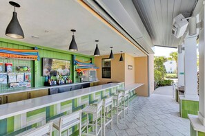 An outdoor bar area with a counter, seating, and hanging pendant lights. - Spacious Solara Resort Home, Near Disney, 4BR, Private Pool, Sleeps up to 12 (Kissimmee)