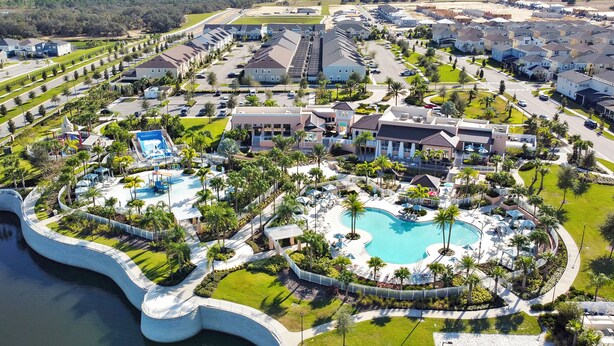 Vista aerea di un resort con una grande piscina, diversi edifici e un elemento d'acqua curvo.