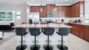 Una cucina moderna con isola centrale, sgabelli da bar, mobili in legno ed elettrodomestici in acciaio inossidabile.
