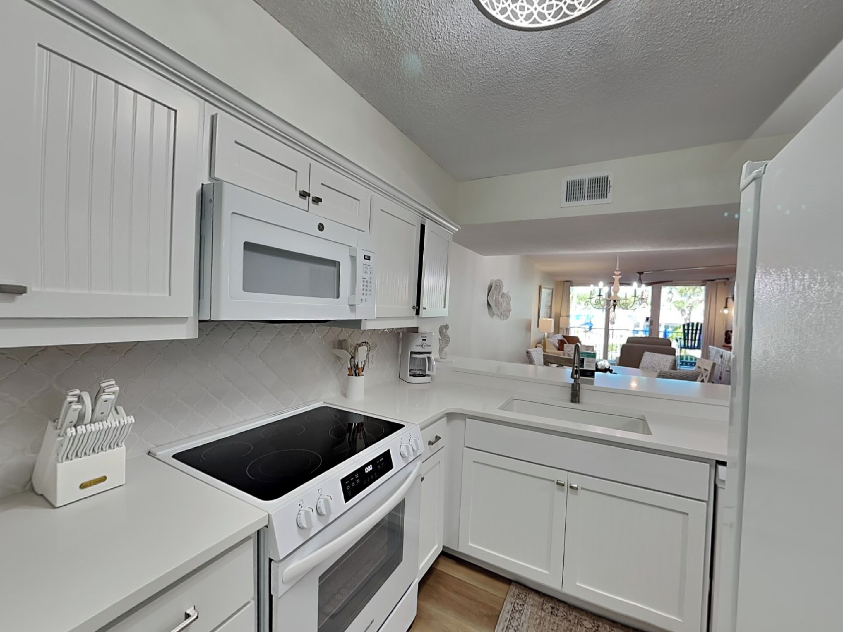 A modern kitchen with white cabinetry, a built-in microwave, an oven, and a stovetop.