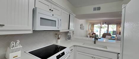 A modern kitchen with white cabinetry, a built-in microwave, an oven, and a stovetop.