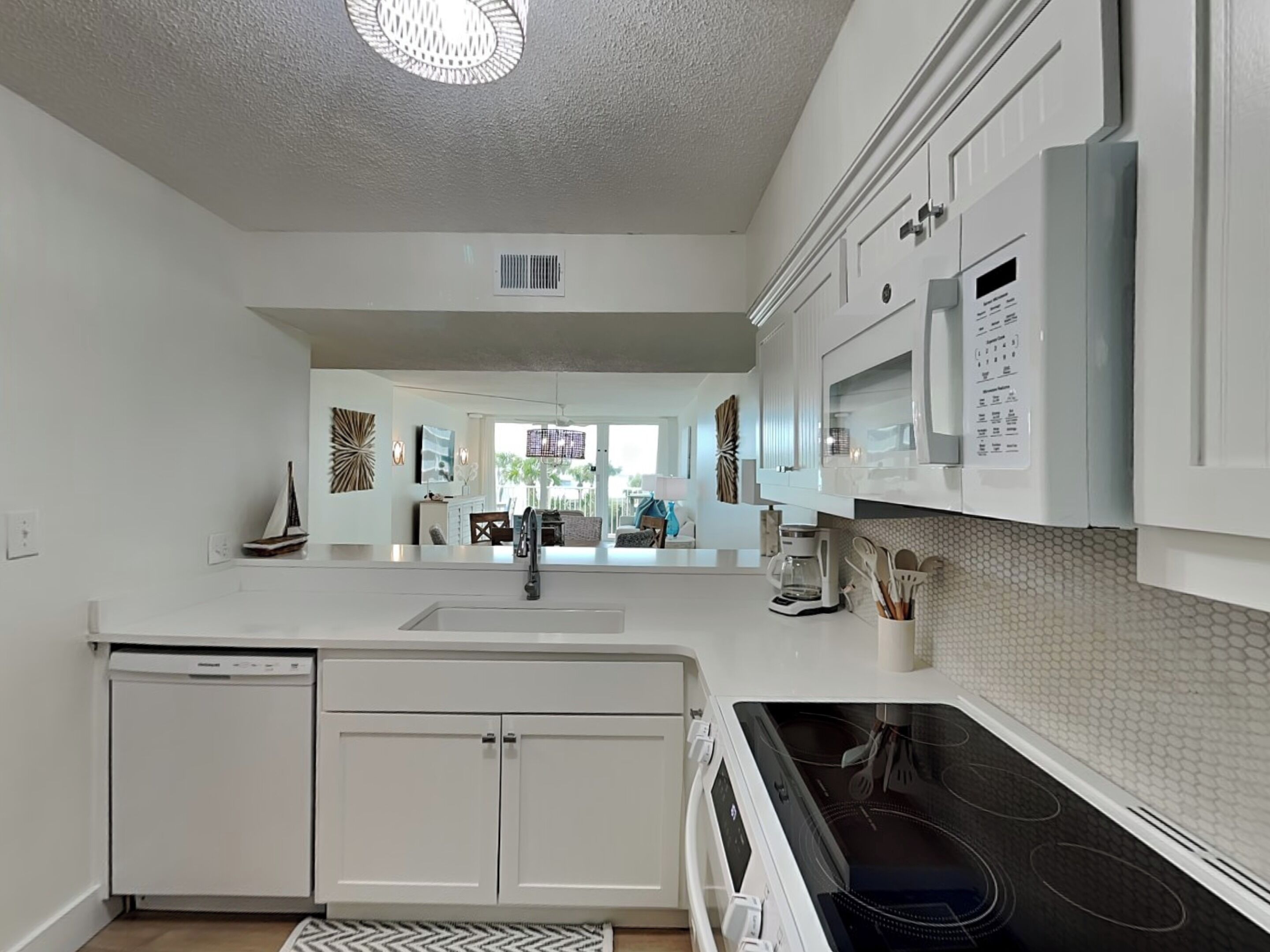 A modern kitchen with white cabinetry, a built-in dishwasher, and a stove.