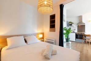 Une chambre d’hôtel comprenant un lit, une table de chevet, une lampe et donnant sur la cuisine.