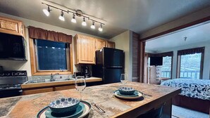 Una cocina con armarios de madera, un refrigerador negro y una mesa de comedor con platos y vasos.