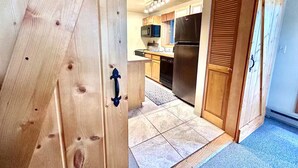 Una cocina con armarios de madera, un refrigerador de acero inoxidable y piso de baldosas.