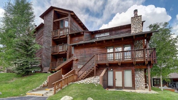 A multi-story log cabin with a stone chimney, wooden balconies, and a stone foundation. - Ski~in~Ski~out~Tyra Aspen~2 Bd/2 Ba~Hot Tubs! (Breckenridge)