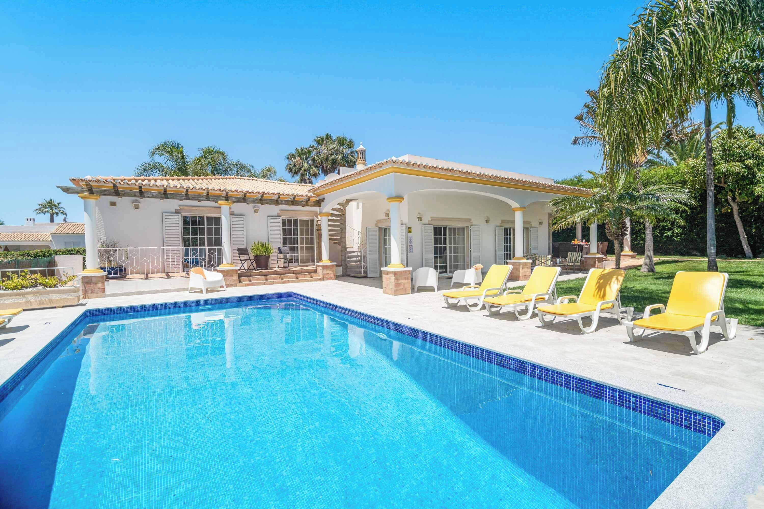A swimming pool with lounge chairs, a covered patio, and a building with columns.