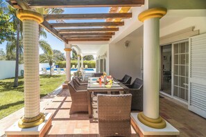 An outdoor patio with wicker furniture, a pergola, and a pool in the background. - Zen Balaia - Four Bedroom Villa, Sleeps 8 (Olhos de Água)