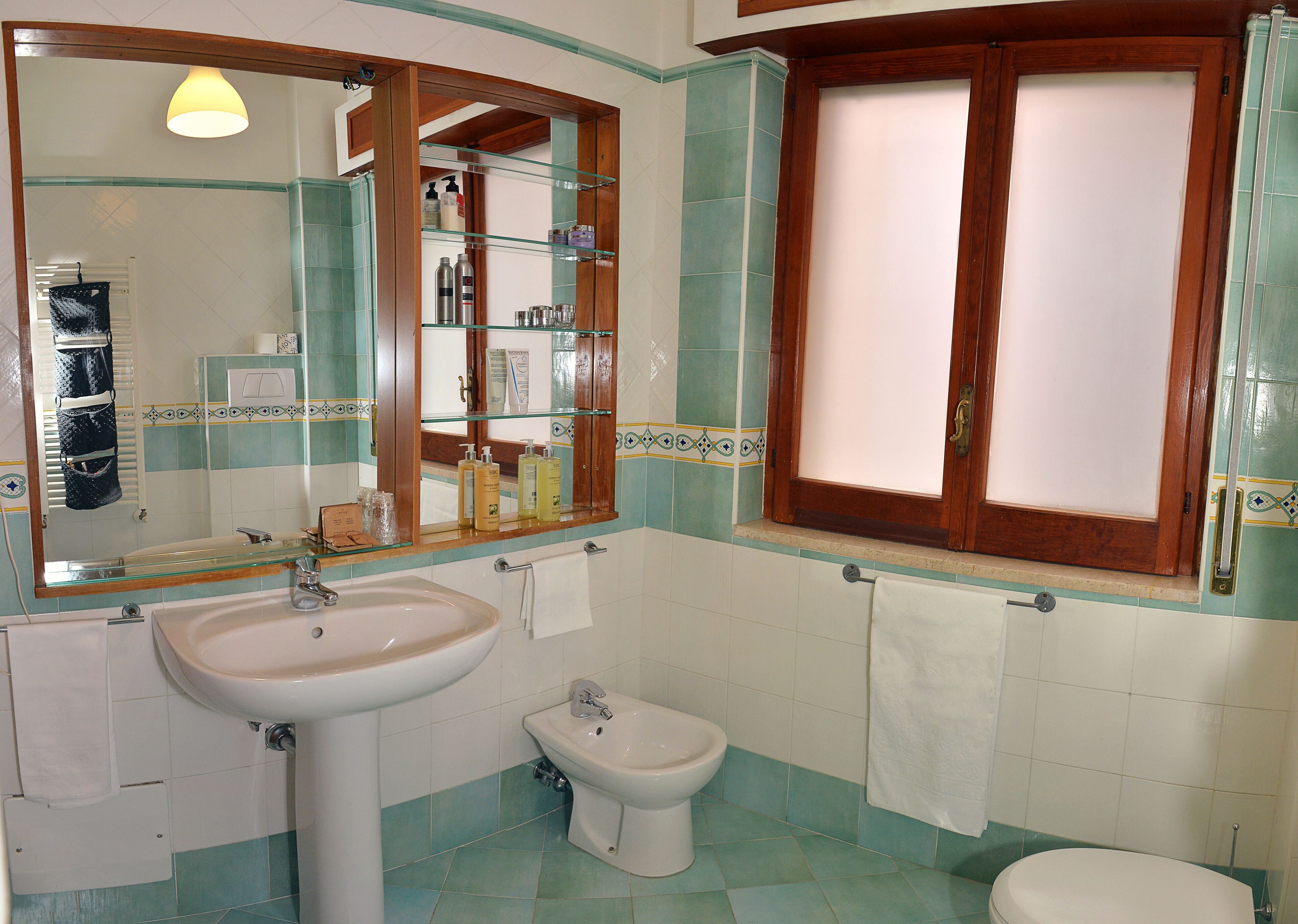 Un baño con lavamanos, bidé y espejo con repisas.