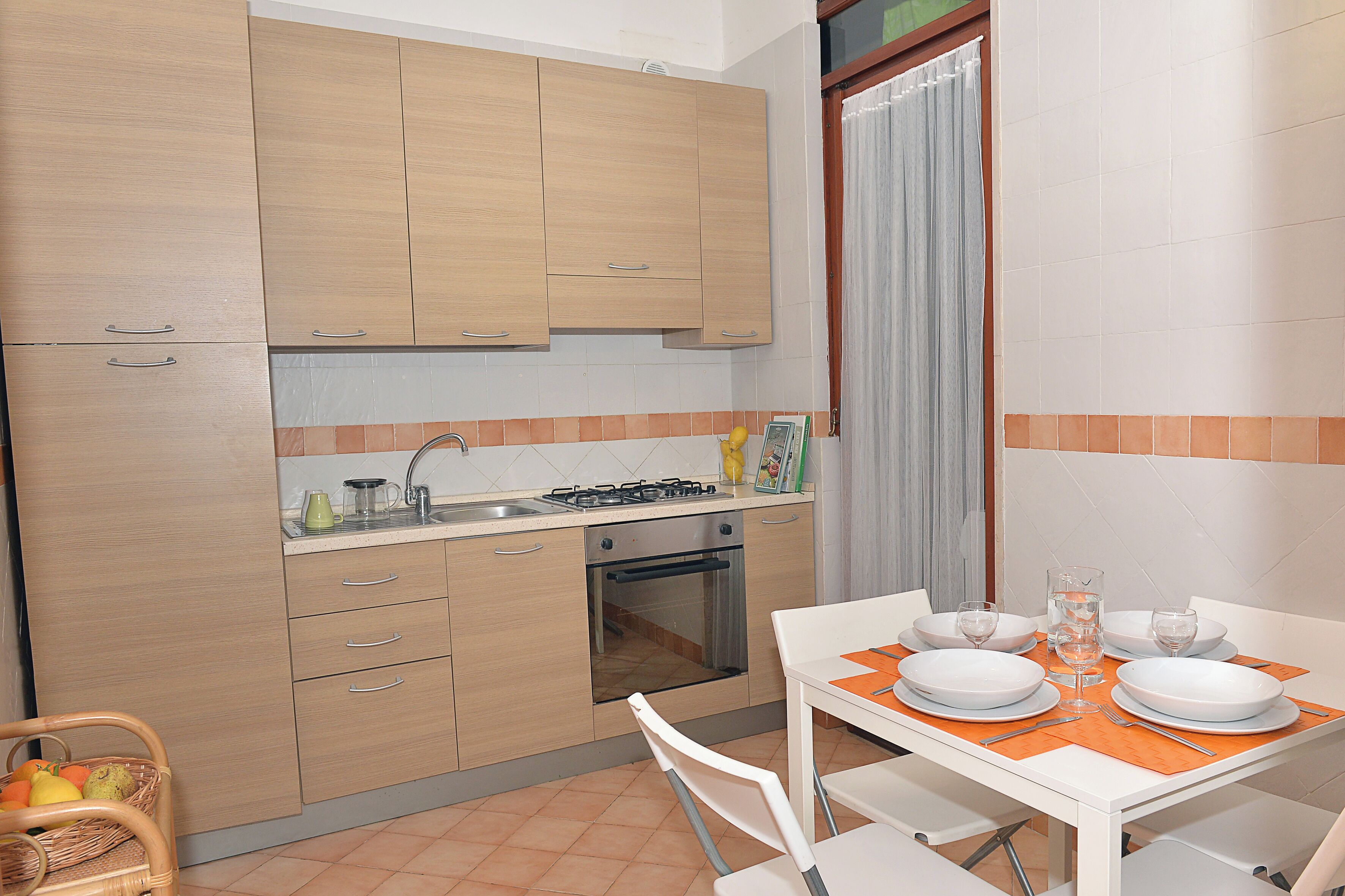 A kitchen with wooden cabinets, a stove, and a dining table set for four.