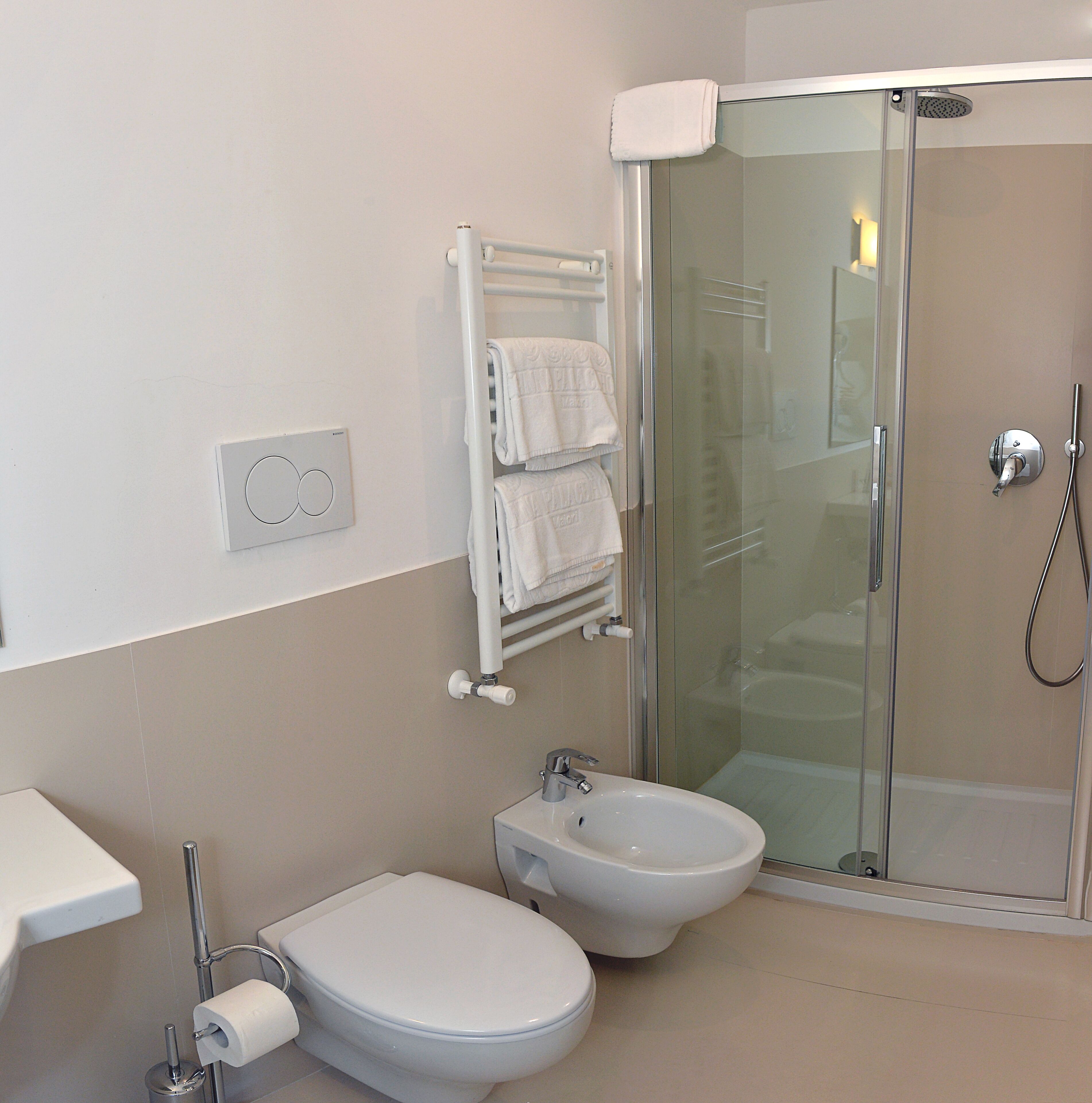 A bathroom with a toilet, bidet, and glass-enclosed shower.