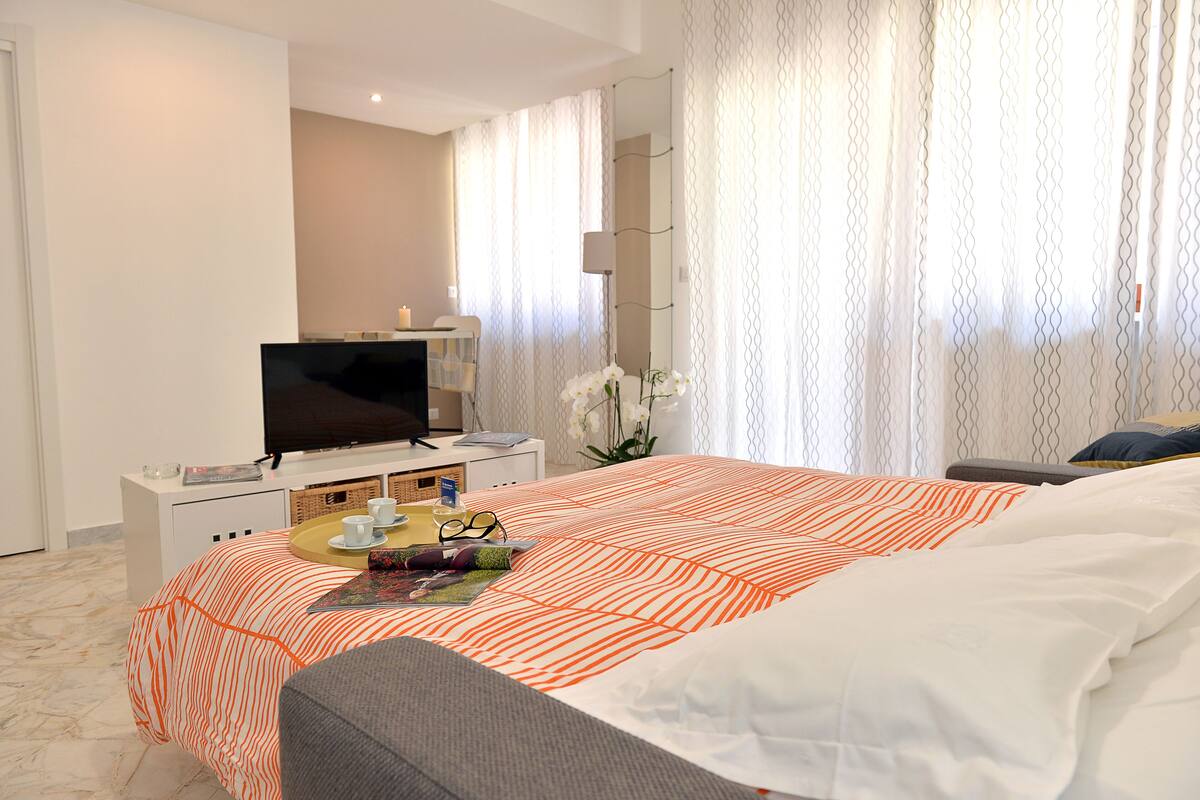 Une chambre d’hôtel avec un lit, une télévision, une table de chevet et une fenêtre avec des rideaux.